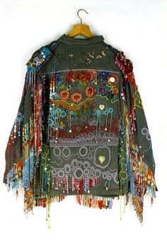 a jacket hanging on a wall with beads and chains attached to the back of it