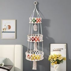 a white bed sitting next to a gray wall and a hanging planter filled with fruit