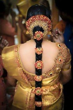 the back of a woman's head with an elaborate braid in gold and red