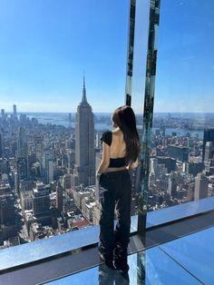 a woman standing on top of a tall building looking out at the cityscape