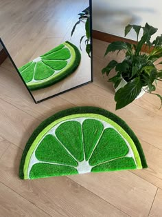 a mirror sitting on top of a wooden floor next to a green slice of lime