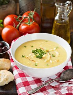 a white bowl filled with soup next to bread and tomatoes