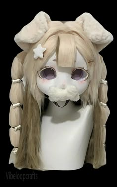 a white mannequin head with long blonde hair and big eyes wearing a wig