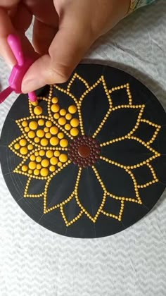 someone is using scissors to decorate a flower on a black and yellow circular piece of paper