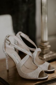 a pair of white shoes sitting on top of a wooden table next to a lamp