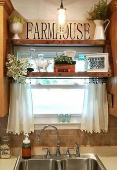 a kitchen sink under a window with the word farmhouse on it's shelf above it