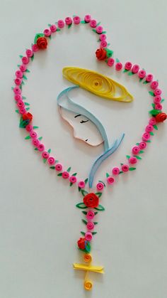 a necklace made out of plastic beads and flowers on a white surface with an image of a woman's face in the center