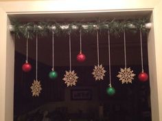 christmas decorations hanging from a window in front of a door with snowflakes on it