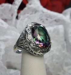 Simulated Rainbow Mystic Topaz Ring Description Lion Design#218 MADE TO ORDER I now offer this is a brand new Art Deco/Victorian reproduction ring in solid sterling silver. The gorgeous filigree ring is set with a simulated Mystic Topaz. The high quality round cut Mystic Topaz is 16mm by 12mm. The inside of the band is marked 925 for sterling. Notice the beautiful craftsmanship of the silver filigree setting. Feel free to ask questions and thanks for looking at my listings. All rings can be size Art Deco Filigree, Wire Jewelry Rings, Mystic Topaz Ring, Victorian Ring, Order Design, Victorian Rings, Luxury Rings, Purple Band, Mystic Topaz