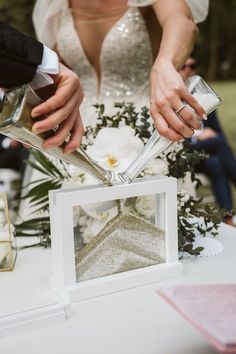 the bride and groom are cutting their wedding cake at the table with silver utensils