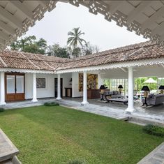 an outdoor living area with lawn and patio furniture in the foreground, surrounded by white pillars