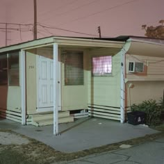 an old mobile home sits on the corner of a street in front of a pink sky