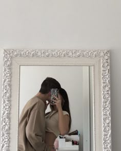 a man and woman standing in front of a mirror