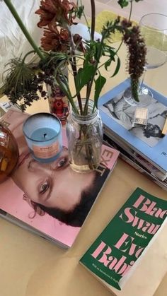 a table topped with books and vases filled with flowers