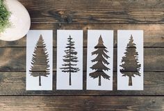 four pine trees cut out on white paper next to a potted plant and vase