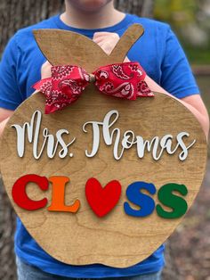 a young boy holding up a wooden sign that says, mrs thomas's class