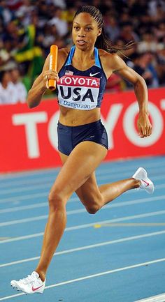 a woman running on a track with an orange object in her hand