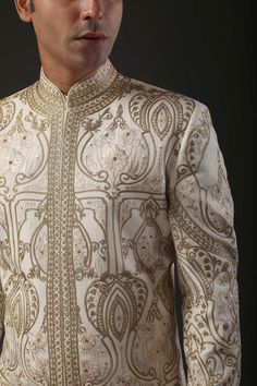 Ivory matka silk sherwani with zari and hand embroidery in floral motifs and silk lined.
Component: 1
Pattern: Embroidered
Type Of Work: Zari
Neckline: Mandarin
Sleeve Type: Full
Fabric: Matka Silk, Lining: Silk 
Color: Ivory
Other Details: 
Zari work
Note: Pant and inner kurta worn by the model is not for sale
Occasion: Groom,Wedding - Aza Fashions Ceremonial Raw Silk Sherwani With Naqshi, Ceremonial Naqshi Sherwani In Raw Silk, Eid Raw Silk Sherwani With Intricate Embroidery, Beige Raw Silk Sherwani With Dabka, Eid Sherwani With Intricate Embroidery In Raw Silk, Cream Embroidered Sets With Traditional Drape, Beige Sherwani With Resham Embroidery For Transitional Season, Gold Silk Sherwani For Eid, Gold Silk Bollywood Sherwani