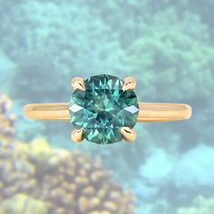 a ring with a green diamond on it in front of corals and seaweed