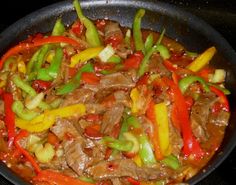 beef and peppers are cooking in a skillet on the stove top, ready to be eaten