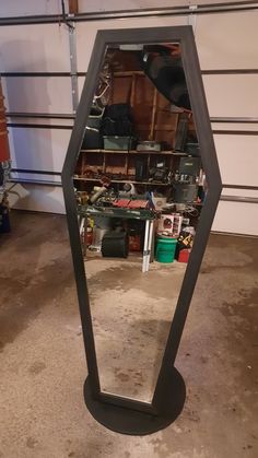 a mirror sitting on top of a floor in front of a garage filled with tools