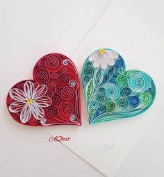 two paper hearts with flowers on them sitting next to each other