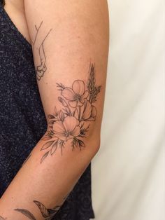 a woman's arm with flowers on it and a hand reaching for the flower