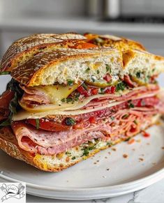 a sandwich with meat, cheese and vegetables on it sitting on top of a white plate