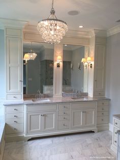 a large bathroom with two sinks and a chandelier above the vanity is shown