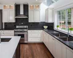 a large kitchen with white cabinets and black counter tops is pictured in this image from the inside