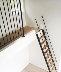 a stair case next to a window in a room with white walls and wooden floors