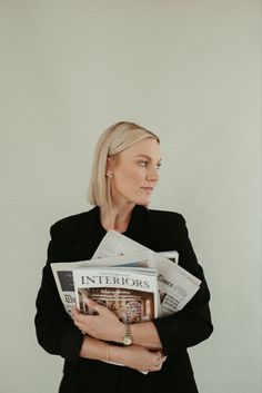 a woman in a black jacket is holding newspapers