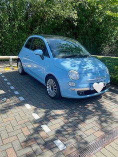 a small blue car parked in front of some bushes