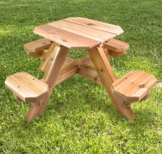 a wooden picnic table sitting on top of a lush green field