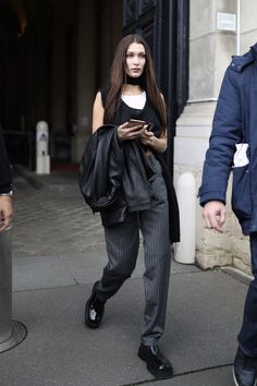 a woman walking down the street while looking at her cell phone