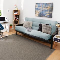 a living room with a couch, chair and computer on the desk in front of it