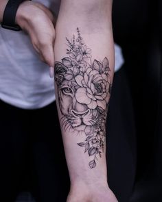 a woman's arm with flowers and a lion tattoo on the left side of her arm