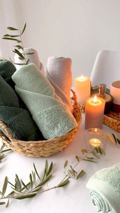 a basket filled with towels next to candles and other items on top of a table