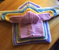 four knitted sweaters sitting on top of a wooden table