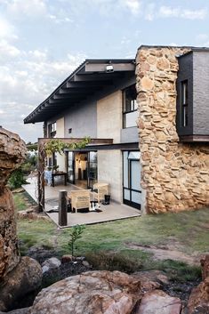 a house that is made out of rocks and has a patio in front of it