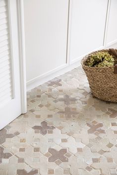 a basket full of flowers sitting on the floor in front of a door with shutters