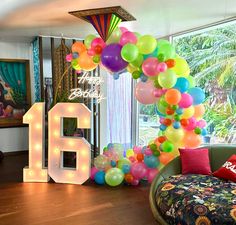 a room filled with balloons and lights next to a large number 16 balloon arch in front of a window