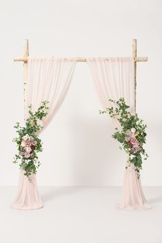 an arch decorated with flowers and greenery for a wedding ceremony or reception in front of a white wall