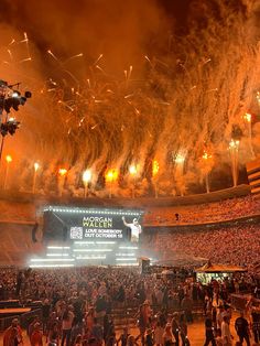 fireworks are lit up in the air above an arena as people watch from the stands