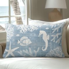 a blue and white pillow sitting on top of a couch next to a window covered in sea life