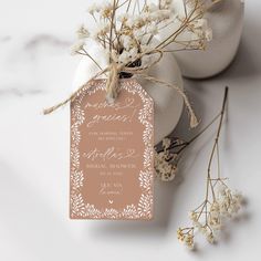 the wedding stationery is on top of some white flowers and two vases with baby's breath