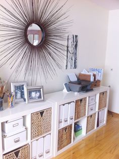 a white shelf with drawers and baskets under a sunburst on the wall above it