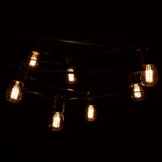 a bunch of light bulbs hanging from a wire in the dark with one bulb turned on