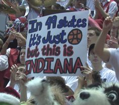 a group of people holding up signs in the middle of a crowd at a basketball game