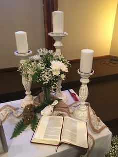 an open book on a table with flowers and candles